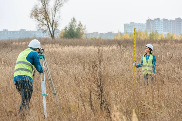 Surveyors measuring land with digital level in field — Stock Photo