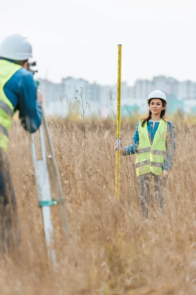 Selective focus of surveyors measuring land with digital level in field — Stock Photo