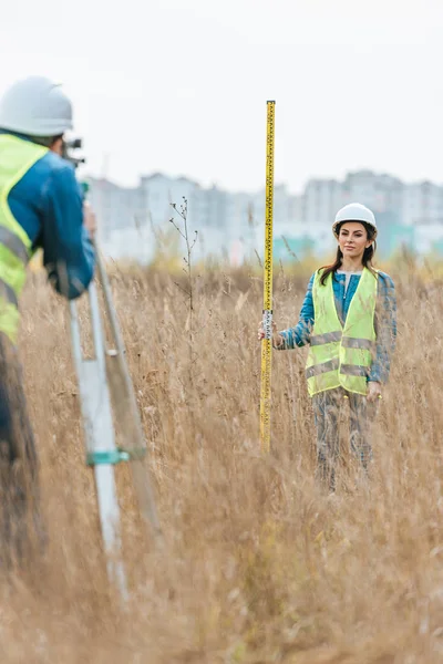 Selektiver Fokus der Vermessungsingenieure, die Land mit digitalem Pegel im Feld messen — Stockfoto