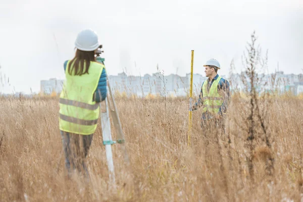Surveyors working with digital level and ruler in field — Stock Photo