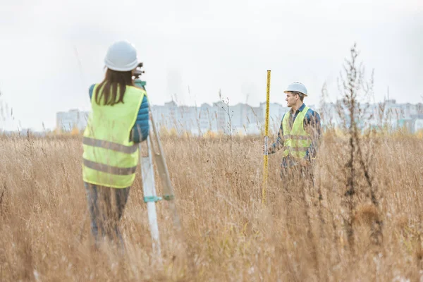 Agrimensores que trabajan con nivel digital y regla en campo - foto de stock