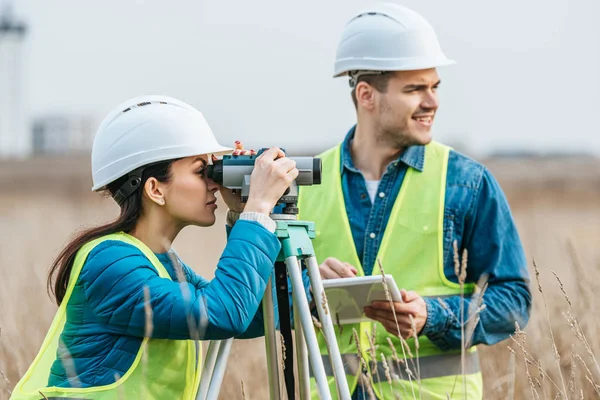 Surveyors working with digital level and tablet in field — Stock Photo