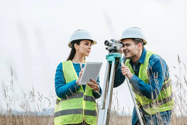 Surveyors working with digital level and tablet in field — Stock Photo