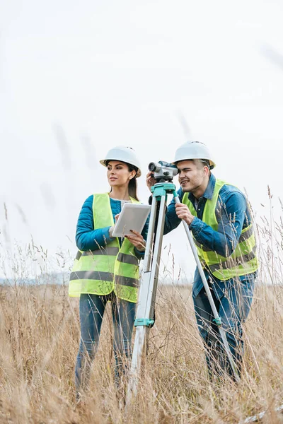Surveyors working with digital level and using tablet in field — Stock Photo