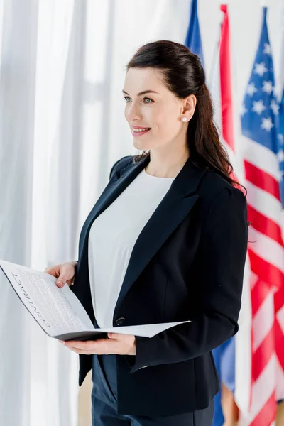 Heureux diplomate tenant dossier avec contrat près du drapeau américain — Photo de stock