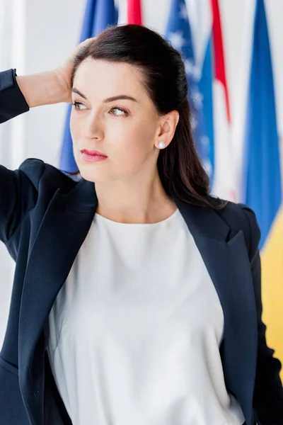 Diplomata atraente tocando o cabelo e olhando para longe — Fotografia de Stock