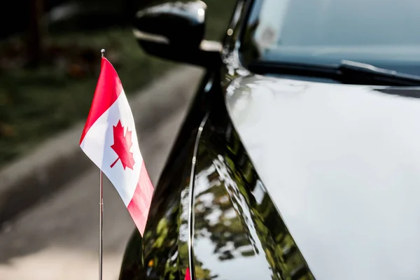 Foco seletivo da bandeira canadense com folha de bordo no carro preto — Fotografia de Stock