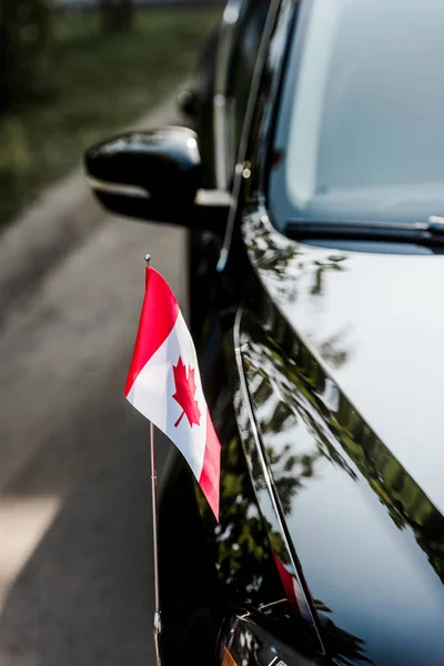 Enfoque selectivo de la bandera canadiense con hoja de arce en coche moderno - foto de stock