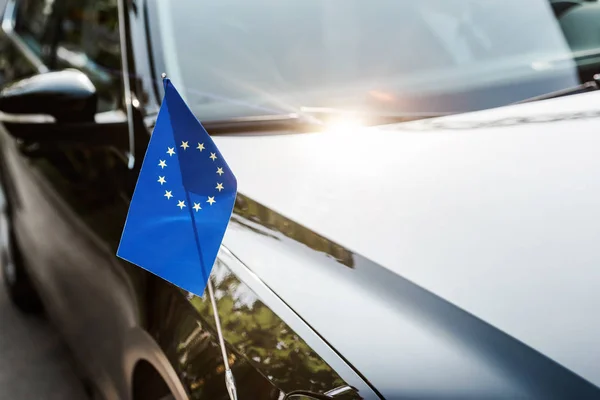 Selektiver Fokus der europäischen Gewerkschaftsfahne in der Nähe des schwarz glänzenden Autos — Stockfoto