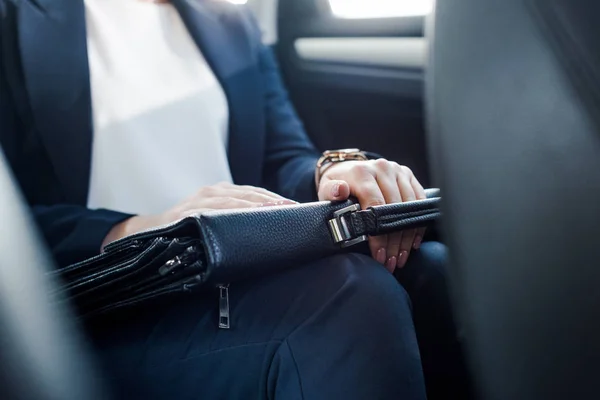 Обрезанный вид на посла, держащего портфель во время сидения в машине — стоковое фото