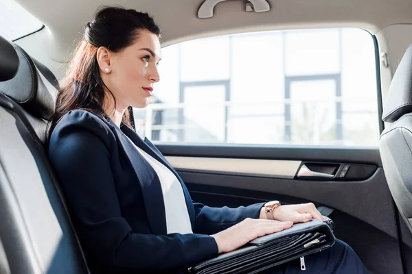 Side view of attractive ambassador holding briefcase while sitting in car — Stock Photo