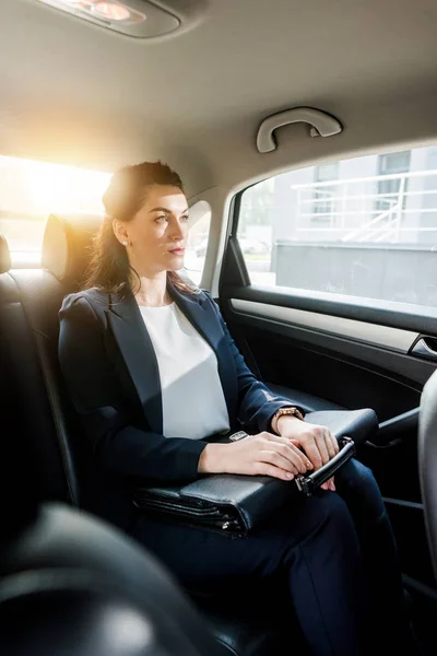 Foyer sélectif de belle ambassadrice tenant la mallette tout en étant assis dans la voiture — Photo de stock