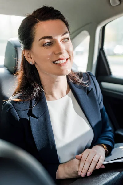 Foco seletivo da mulher feliz no desgaste formal sentado no carro com as mãos apertadas — Fotografia de Stock