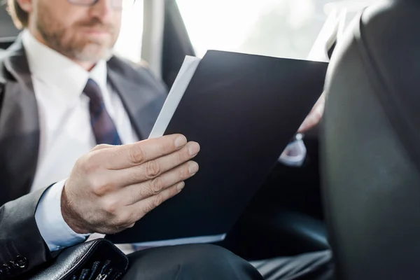 Selective focus of bearded diplomat holding folder in car — Stock Photo