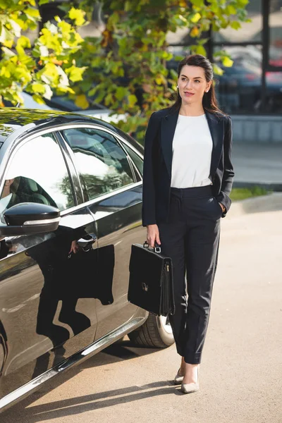 Beau diplomate debout avec la main dans la poche près de la voiture — Photo de stock