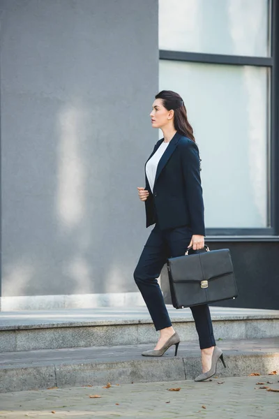 Seitenansicht attraktiver Diplomat mit Aktentasche und Fuß in der Nähe von Gebäude — Stockfoto