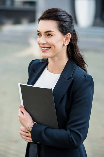 Attractive diplomat holding folder and smiling outside — Stock Photo