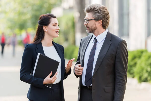 Handsome man and attractive woman in formal wear talking outside — Stock Photo