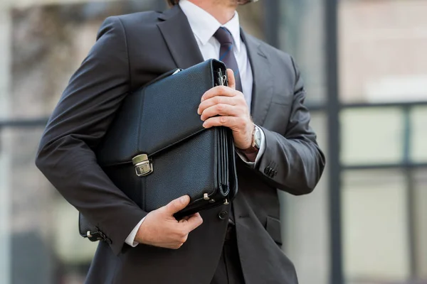 Обрезанный вид человека, держащего кожаный портфель снаружи — стоковое фото