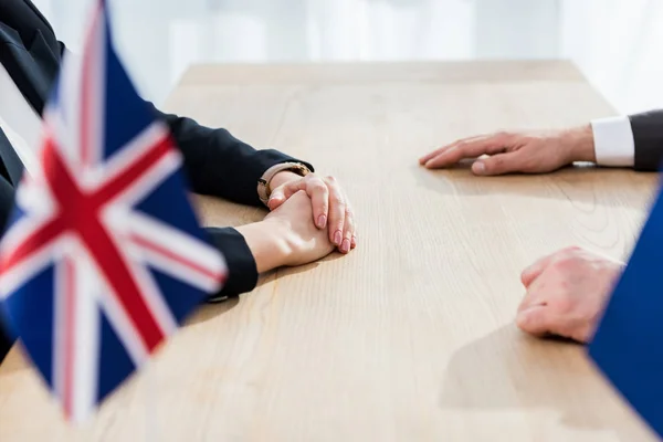 Vue recadrée des ambassadeurs assis près du drapeau du royaume uni — Photo de stock