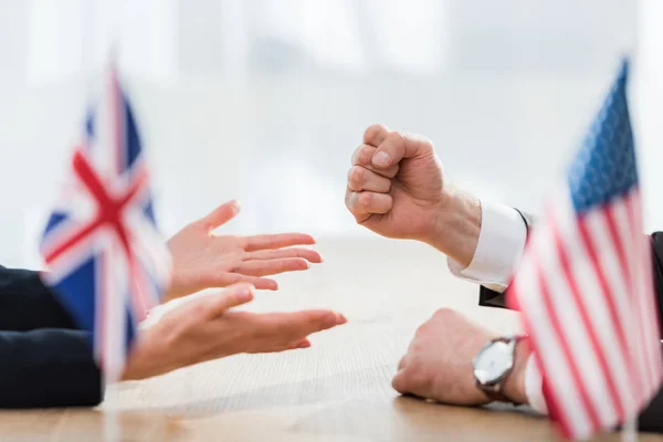 Vista cortada de diplomatas gesticulando perto de bandeiras dos eua e reino unido — Fotografia de Stock