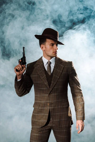 Красивий гангстер в капелюсі тримає пістолет біля диму — стокове фото