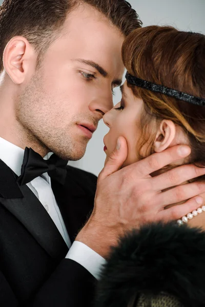 Enfoque selectivo de hombre guapo tocando la cara de mujer atractiva aislado en blanco - foto de stock