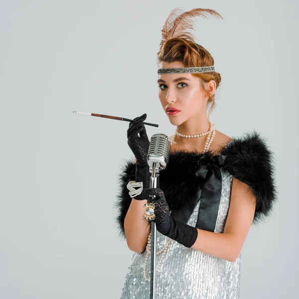 Femme élégante avec porte-cigarette près microphone rétro isolé sur gris — Photo de stock