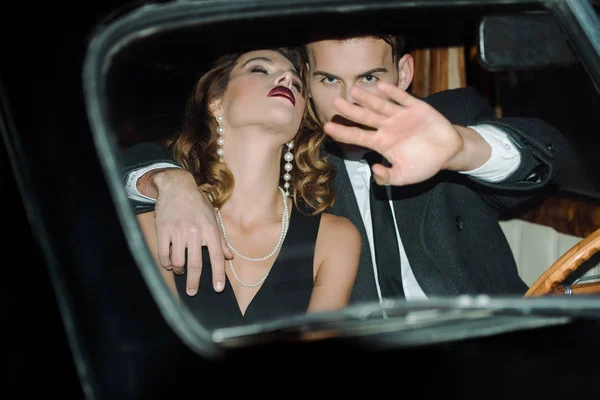 Foco seletivo do homem gesticular enquanto cobre o rosto e sentado com mulher atraente no carro — Fotografia de Stock
