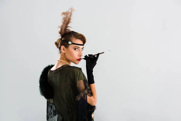 Aristocratic woman with cigarette holder smoking isolated on grey — Stock Photo