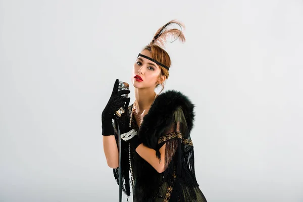 Femme élégante debout et touchante microphone vintage isolé sur blanc — Photo de stock