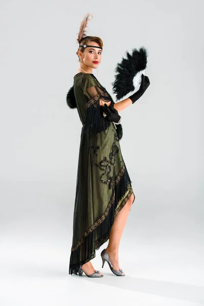 Привлекательная и аристократичная женщина держит перьевой веер на сером — стоковое фото
