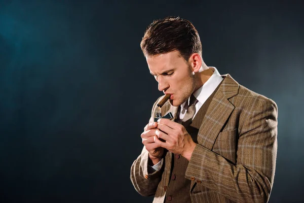 Handsome gangster smoking cigar on black — Stock Photo