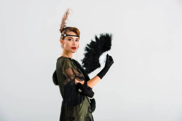 Aristocrática mujer sosteniendo negro pluma ventilador aislado en gris - foto de stock