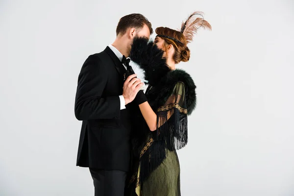 Man and woman standing and covering faces with feather fan isolated on white — Stock Photo