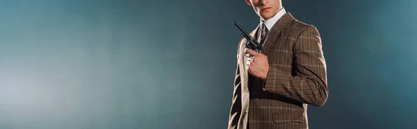 Panoramic shot of man holding gun on black — Stock Photo