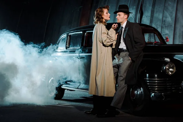 Handsome gangsters standing near retro car and smoke outside — Stock Photo