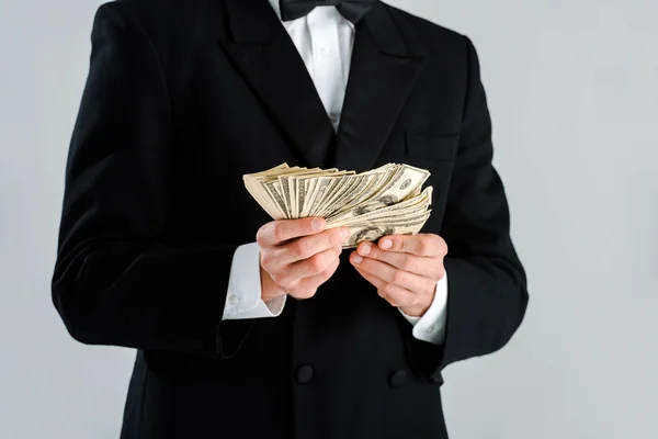 Обрізаний вид на багатого чоловіка в костюмі, що тримає доларові банкноти ізольовані на сірому — стокове фото