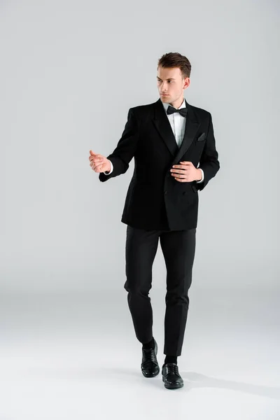 Hombre guapo y rico en traje de pie y gestos en blanco - foto de stock