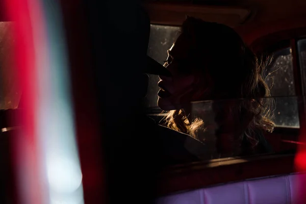 Selective focus of attractive woman near man in hat sitting in retro car — Stock Photo