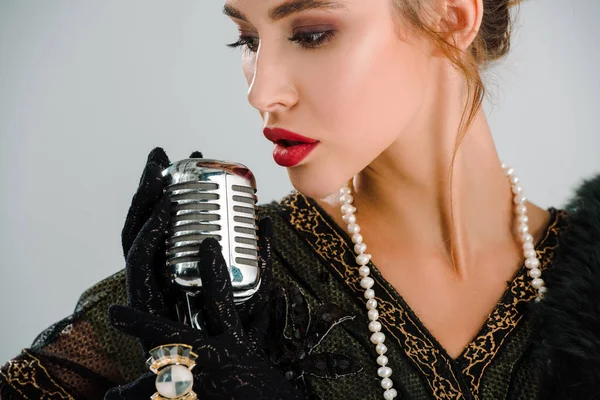 Bela mulher tocando microfone vintage isolado em cinza — Fotografia de Stock