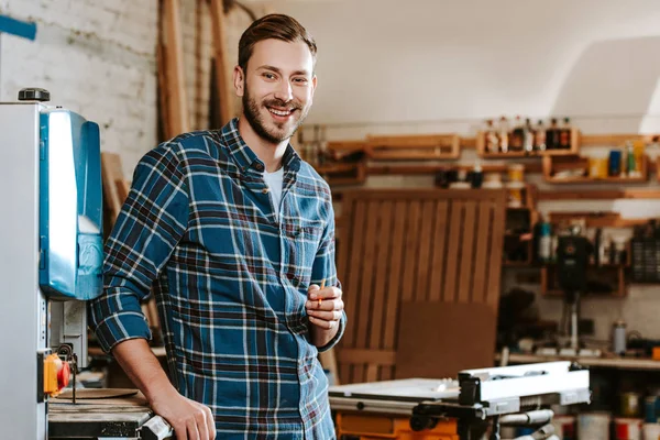 Cheerful carpenter holding pencil in workshop — Stock Photo