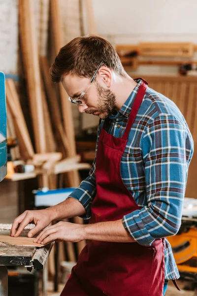 Schöner Tischler mit Schutzbrille und Schürze in der Werkstatt — Stockfoto