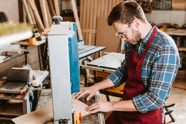 Selektiver Fokus des bärtigen Tischlers in Schutzbrille und Schürze mittels CNC-Maschine — Stockfoto