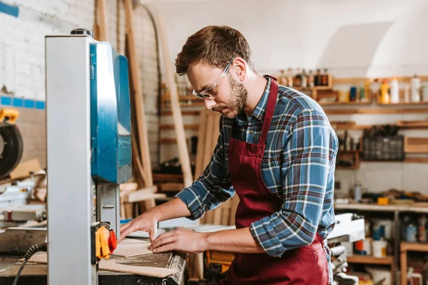 Селективная фокусировка плотника в защитных очках и фартуке с помощью cnc машины — стоковое фото