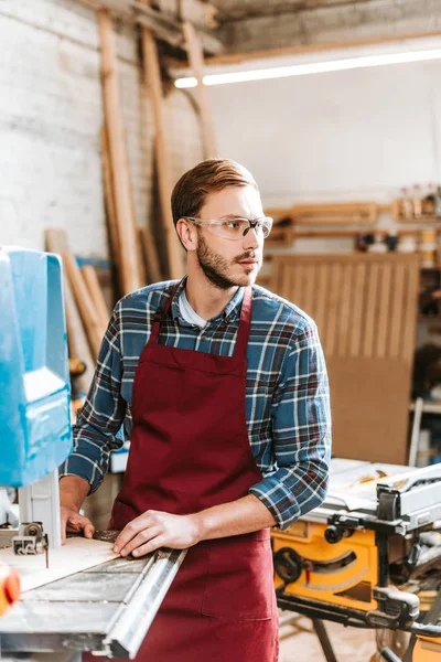 Selektiver Fokus eines hübschen Holzarbeiters mit CNC-Maschine in der Werkstatt — Stockfoto