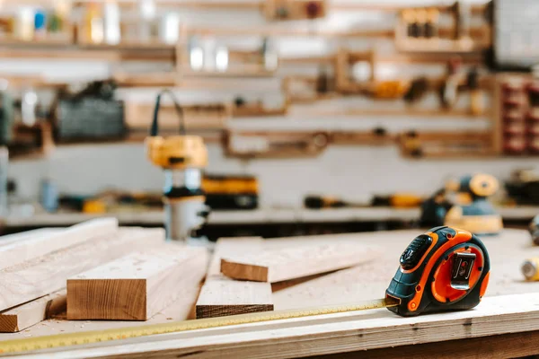 Enfoque selectivo de cinta métrica cerca de tablones de madera en la mesa - foto de stock