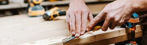 Panoramic shot of carpenter cutting wooden plank — Stock Photo