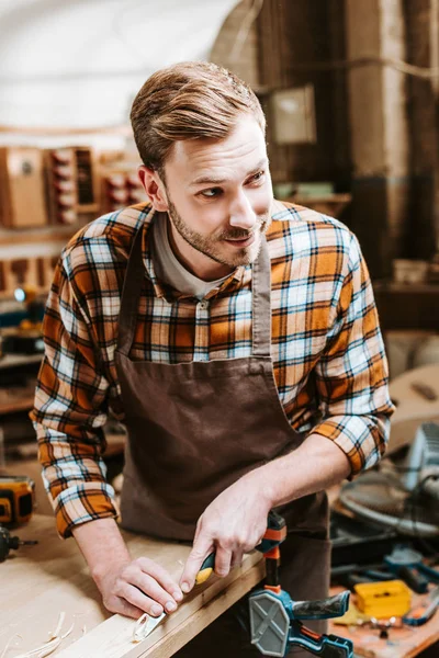 Tischler hält Meißel beim Schnitzen von Holz in Werkstatt — Stockfoto