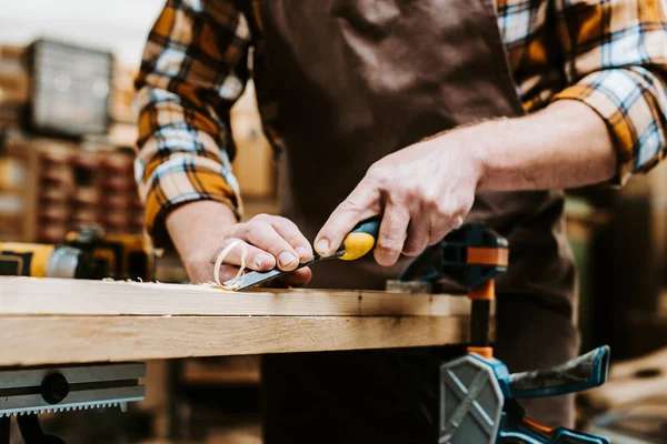 Cropped view of woodworker holding chisel while carving wood in workshop — Stock Photo